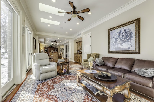 living area with a skylight, crown molding, wood finished floors, and recessed lighting