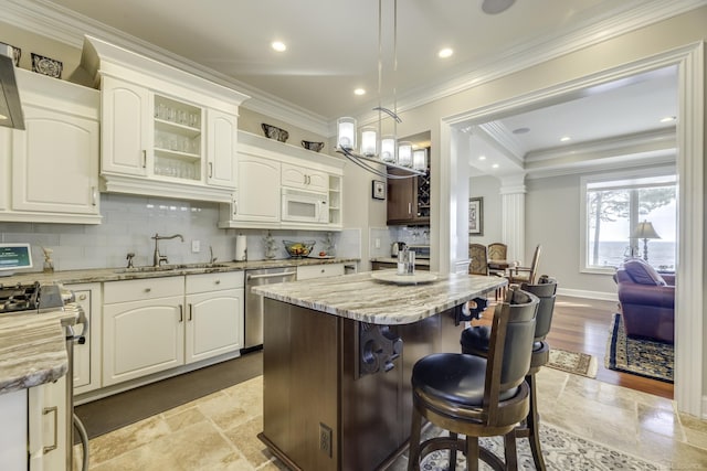 kitchen with stainless steel appliances, a sink, light stone countertops, tasteful backsplash, and a kitchen bar