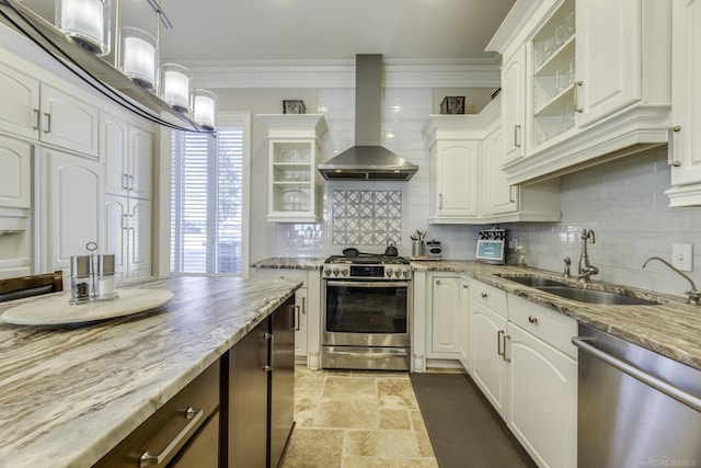 kitchen featuring glass insert cabinets, appliances with stainless steel finishes, crown molding, wall chimney range hood, and a sink