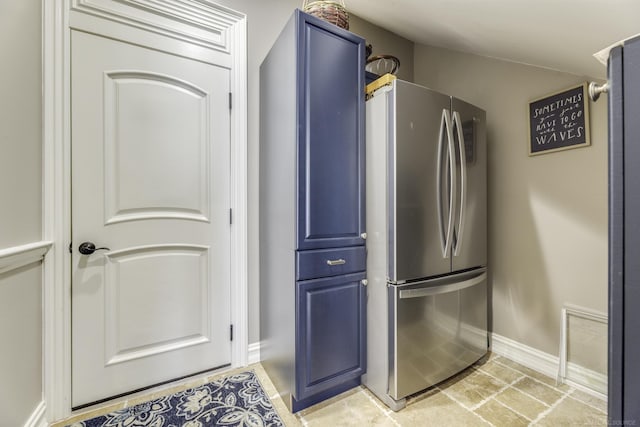 kitchen featuring blue cabinets, baseboards, and freestanding refrigerator