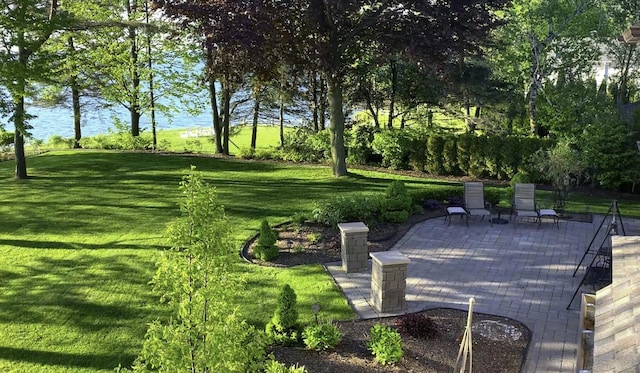 view of community featuring a yard, a water view, and a patio