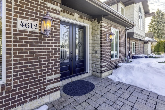 view of exterior entry featuring brick siding and french doors