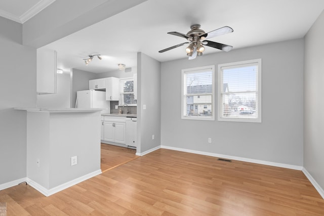 unfurnished living room featuring a ceiling fan, light wood-type flooring, visible vents, and baseboards