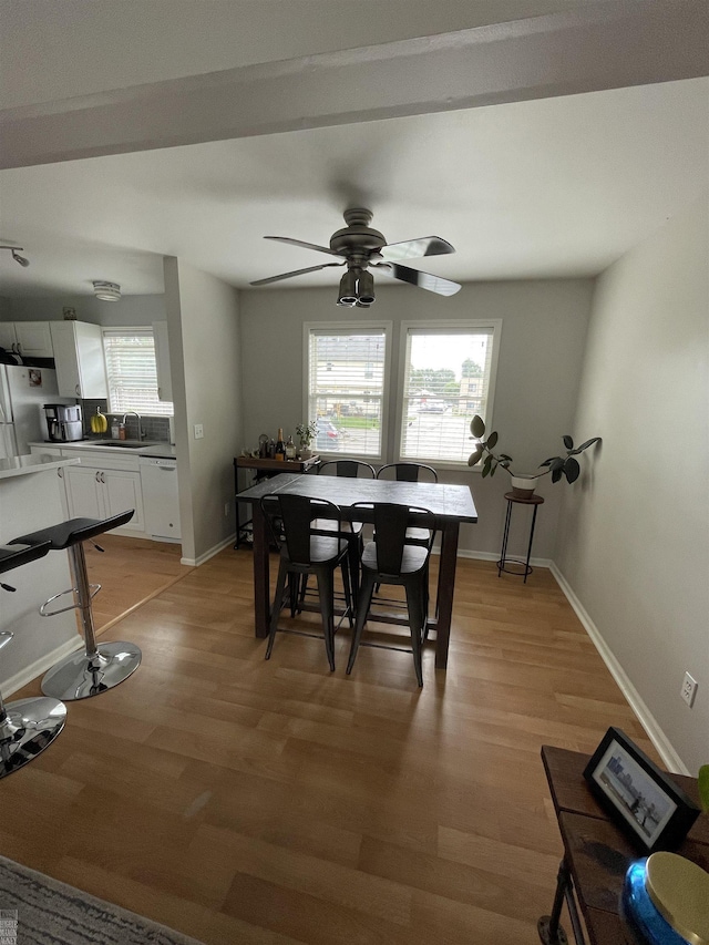 dining room with a healthy amount of sunlight, light wood-type flooring, baseboards, and ceiling fan