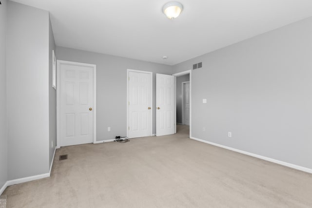 unfurnished bedroom with light colored carpet, visible vents, and baseboards