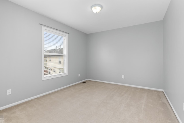 spare room featuring baseboards, visible vents, and light colored carpet