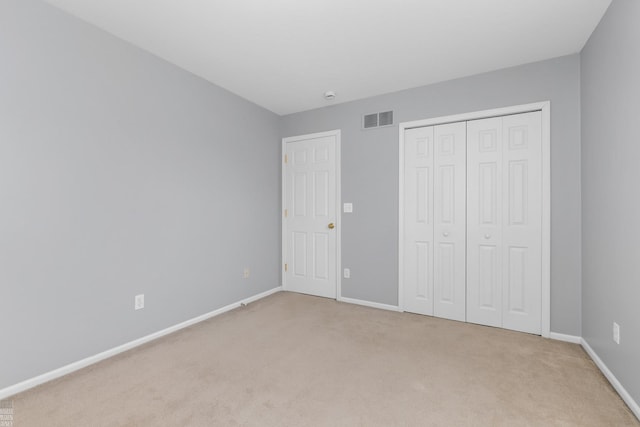 unfurnished bedroom featuring light carpet, baseboards, visible vents, and a closet