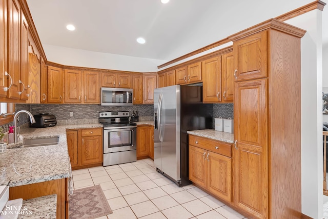 kitchen with stainless steel appliances, decorative backsplash, brown cabinetry, light tile patterned flooring, and a sink