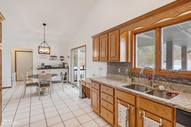 kitchen with light tile patterned floors, a sink, vaulted ceiling, backsplash, and dishwasher