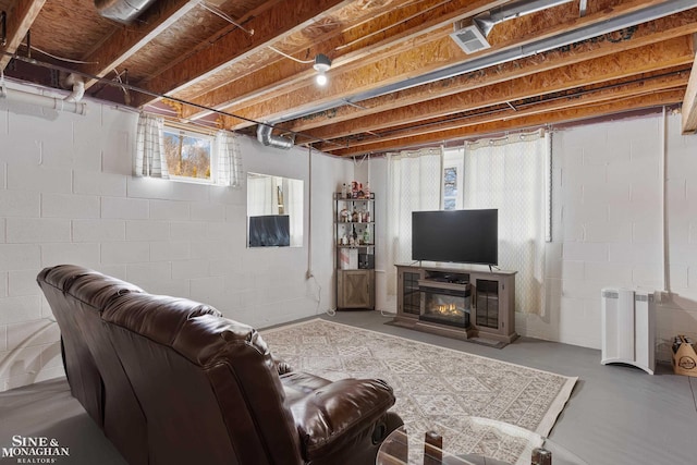 living room with a glass covered fireplace and concrete floors