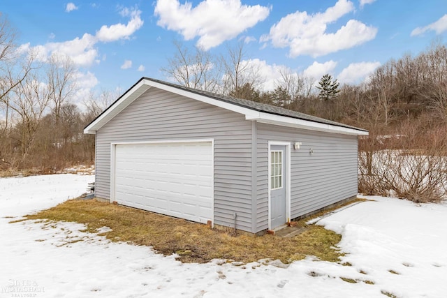 snow covered garage featuring a detached garage