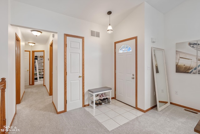 foyer featuring light carpet, light tile patterned floors, and visible vents