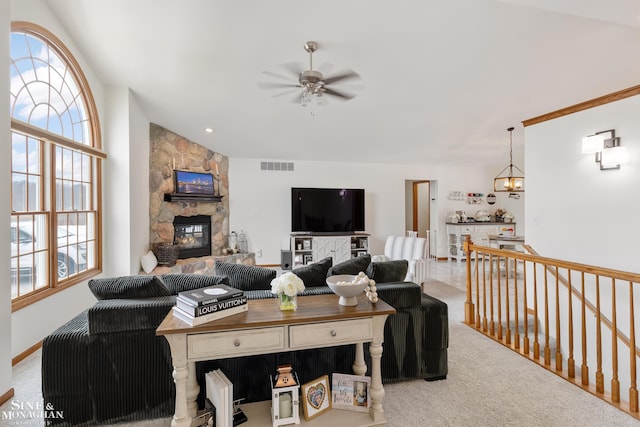 living room with carpet, a fireplace, visible vents, vaulted ceiling, and ceiling fan with notable chandelier