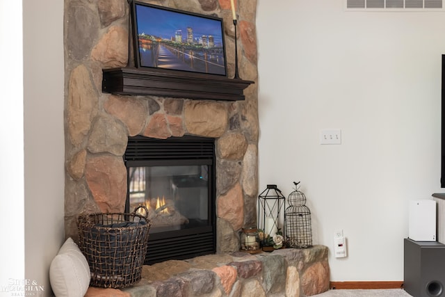 room details featuring visible vents, a stone fireplace, and baseboards