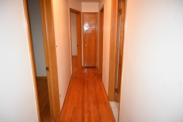 hallway featuring light wood finished floors and baseboards