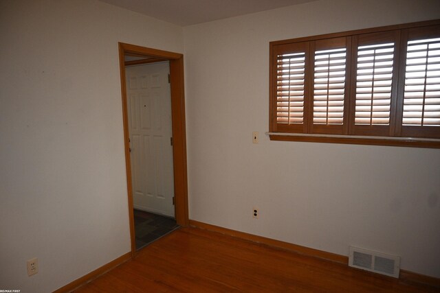 spare room featuring visible vents, baseboards, and wood finished floors