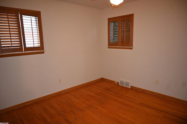 spare room with visible vents, ceiling fan, baseboards, and wood finished floors