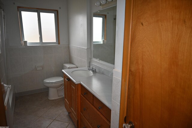 full bath with tile patterned flooring, plenty of natural light, vanity, and tile walls