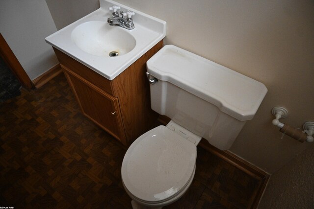 half bathroom featuring vanity, toilet, and baseboards