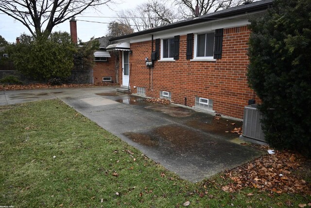 view of side of home featuring a yard, brick siding, concrete driveway, and central air condition unit