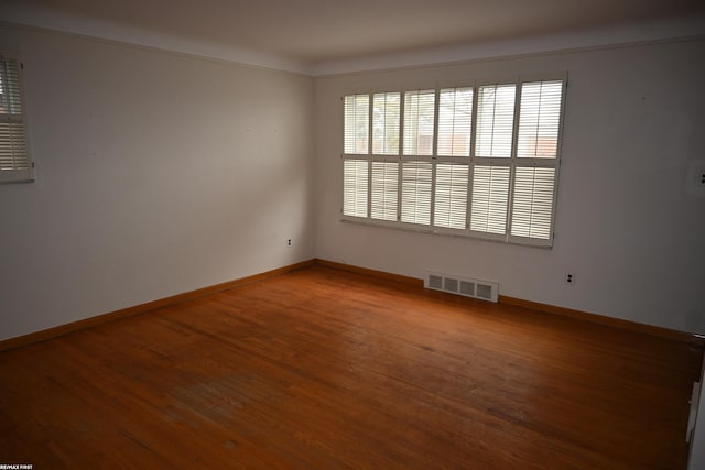 unfurnished room with baseboards, visible vents, and wood finished floors