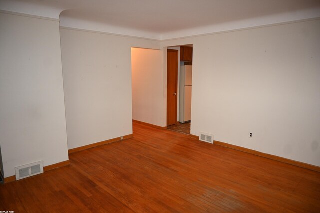 empty room with baseboards, visible vents, and wood finished floors