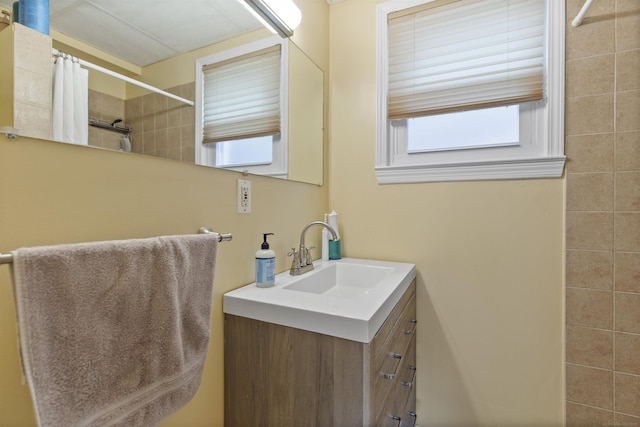 bathroom featuring tiled shower and vanity