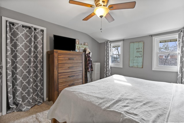 carpeted bedroom with radiator, ceiling fan, and vaulted ceiling