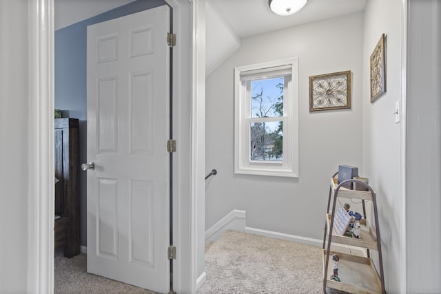 hall featuring carpet floors, baseboards, and lofted ceiling