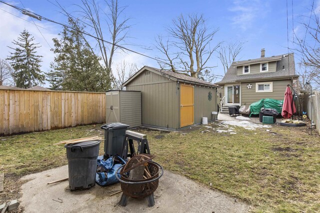 view of shed with entry steps, a fenced backyard, and a fire pit