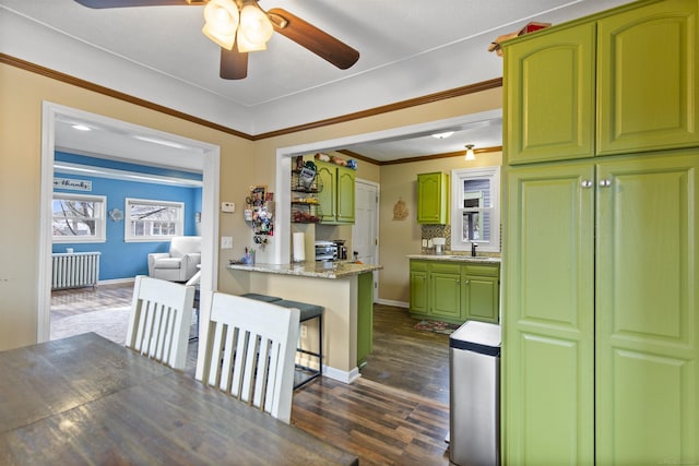 kitchen featuring ornamental molding, dark wood-type flooring, a sink, green cabinets, and a wealth of natural light