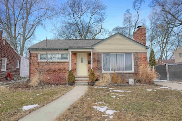 bungalow-style house with brick siding, a chimney, and roof with shingles