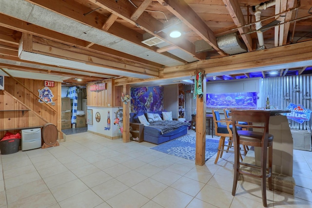 finished basement featuring wooden walls and light tile patterned floors