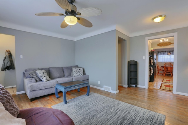 living area with baseboards, visible vents, wood finished floors, and ceiling fan with notable chandelier