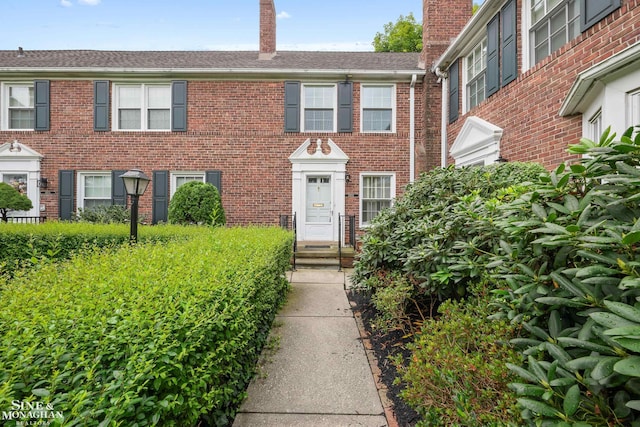 view of front of home featuring brick siding and a chimney