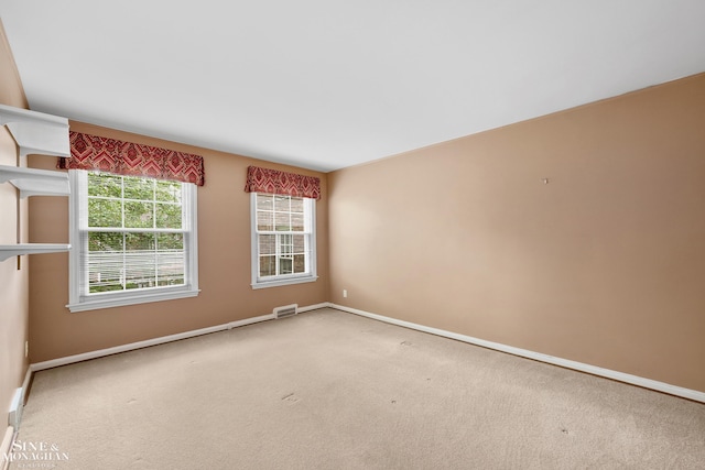 carpeted spare room with visible vents and baseboards