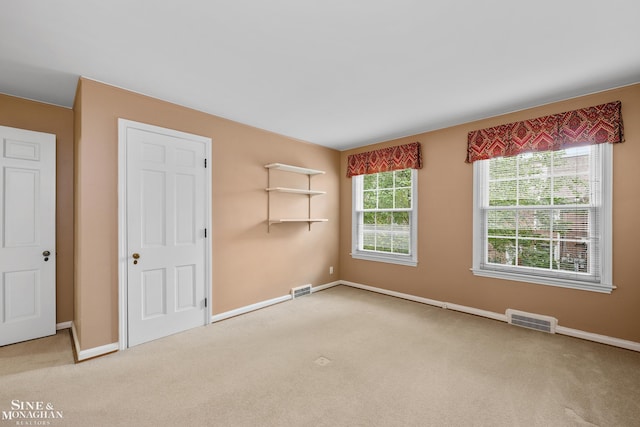 empty room with baseboards, visible vents, and carpet flooring