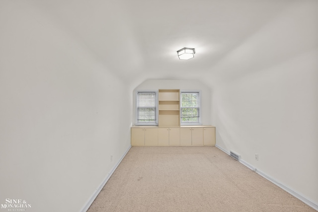 bonus room with lofted ceiling, visible vents, baseboards, and light colored carpet