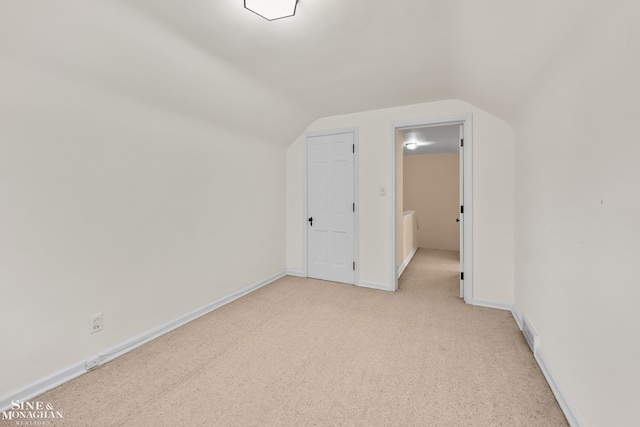 additional living space featuring baseboards, vaulted ceiling, and light colored carpet