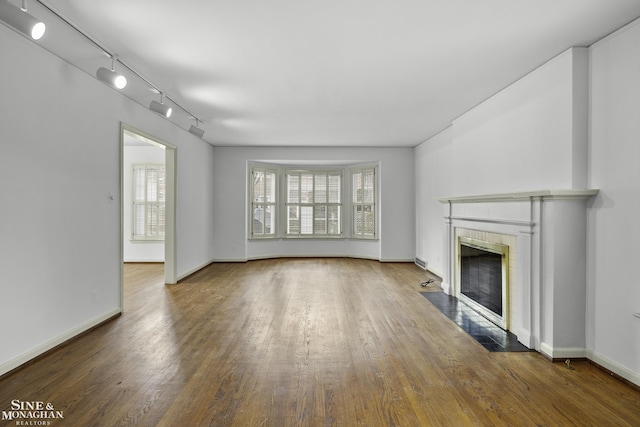 unfurnished living room featuring a fireplace with flush hearth, baseboards, and wood finished floors