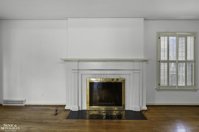 details with baseboards, a fireplace, visible vents, and wood finished floors