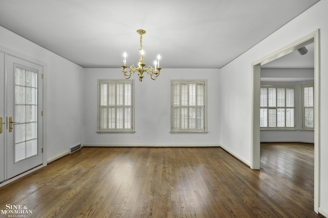 unfurnished dining area with a notable chandelier, wood finished floors, visible vents, and baseboards