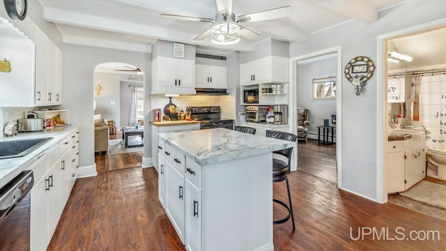 kitchen with arched walkways, a ceiling fan, dishwashing machine, black range with electric cooktop, and beam ceiling