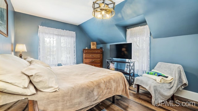 bedroom featuring baseboards, vaulted ceiling, and wood finished floors