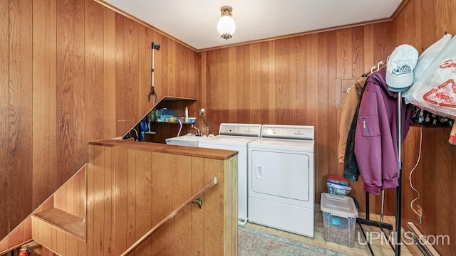 laundry room featuring cabinet space, wood walls, a sink, and independent washer and dryer