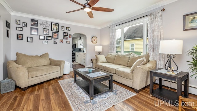 living room featuring ceiling fan, arched walkways, wood finished floors, and ornamental molding