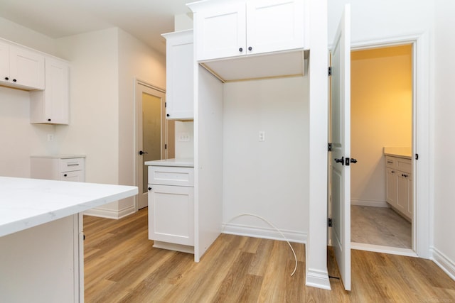 interior space featuring light stone counters, light wood-type flooring, and white cabinets