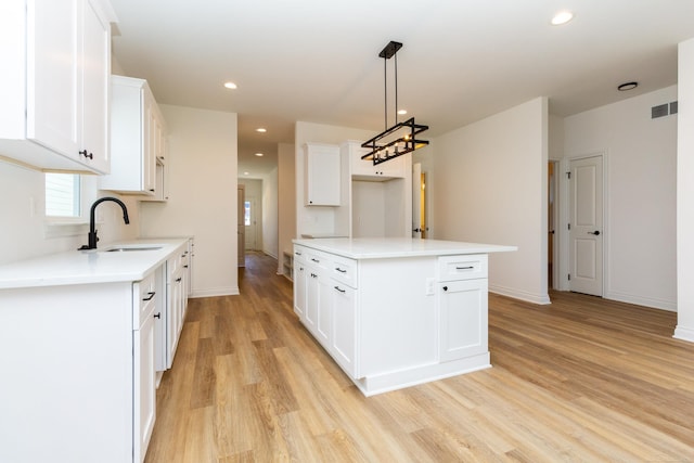 kitchen featuring white cabinetry, a sink, light wood-style flooring, and recessed lighting