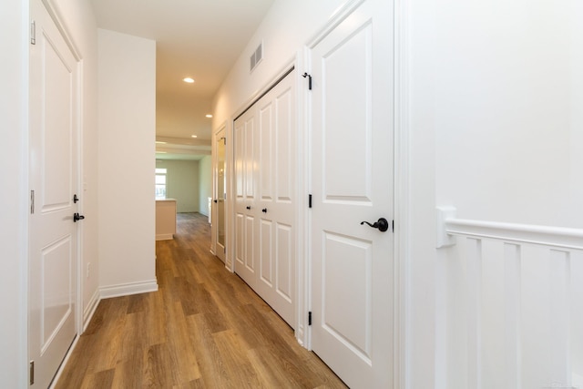 corridor with light wood finished floors, wainscoting, visible vents, and recessed lighting