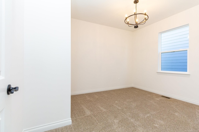 carpeted spare room with visible vents, a notable chandelier, and baseboards